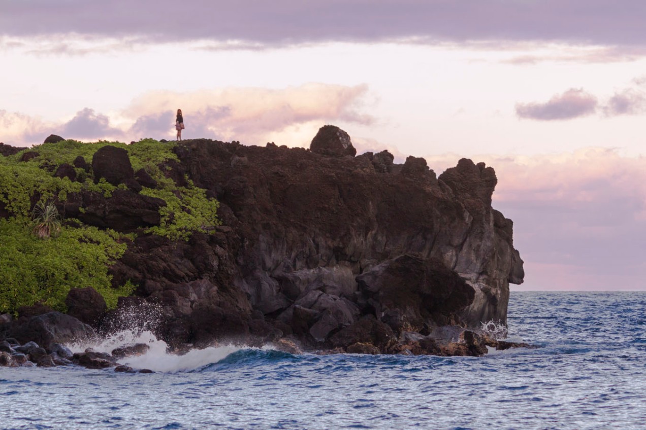 woman standing atop the rocky maui sea cliff